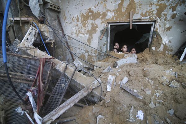 Գազայի Ռաֆահ քաղաքում պաղեստինցի երեխաները նայում են շենքի փլատակների տակից, որոնք ավիրվել են իսրայելական ավիահարվածներից: - Sputnik Արմենիա