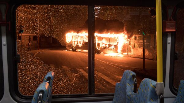 Вид горящего автобуса через разбитое стекло другого автобуса во время во время всеобщей забастовки в Рио де Жанейро (28 апреля 2017). Бразилия - Sputnik Армения