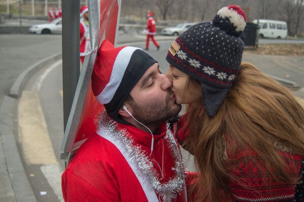 Влюбленные целуются после участия в благотворительном марафоне Санта-Клаусов в Ереване - Sputnik Армения