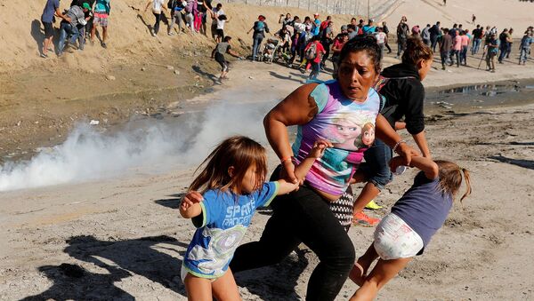 39-летняя мигрантка из Гондураса, с пятилетними дочерьми-близнецами убегает от распыленного слезоточивого газа на границе между США и Мексикой (25 ноября 2018). Тихуана - Sputnik Արմենիա