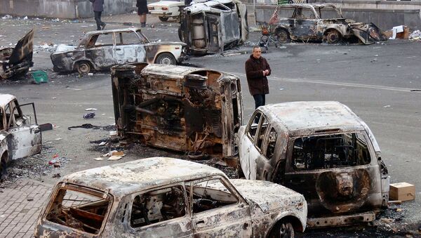 Мужчина среди сожженных автомобилей, оставленных после ночных беспорядков (2 марта 2008). Еревaн - Sputnik Армения