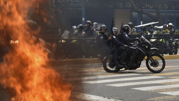 Спецназовцы на мотоцикле проезжают мимо пожара во время акции протеста против правительства президента Николаса Мадуро (23 января 2019). Каракас - Sputnik Армения