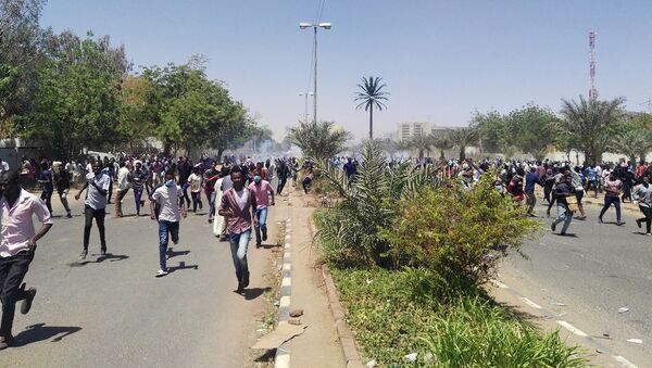 Протестующие в Судане убегают от сотрудников сотрудников полиции, стреляющих слезоточивым газом во время протеста у военного штаба (7 апреля 2019). Хартум - Sputnik Армения
