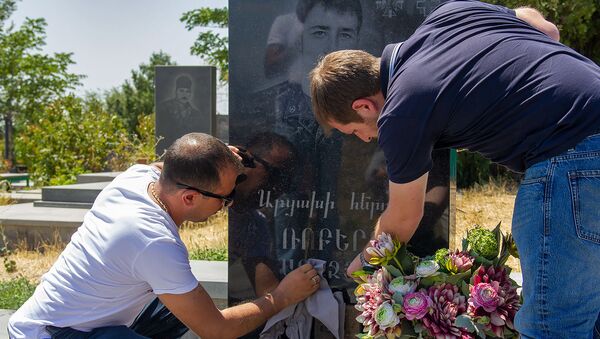 Родственники Роберта Абаджяна очищают надгробную плиту героя  - Sputnik Армения
