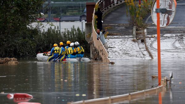 Мужчина разговаривает со спасателями, обыскивающими затопленный район после тайфуна Хагибис (14 октября 2019). Япония - Sputnik Արմենիա