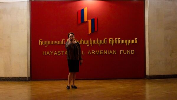 Женщина с телефоном у логотипа Всеармянского фонда Айастан - Sputnik Армения