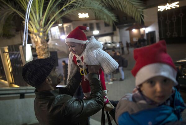 Мужчина играет с ребенком до начала рождественской мессы в Газе  - Sputnik Армения