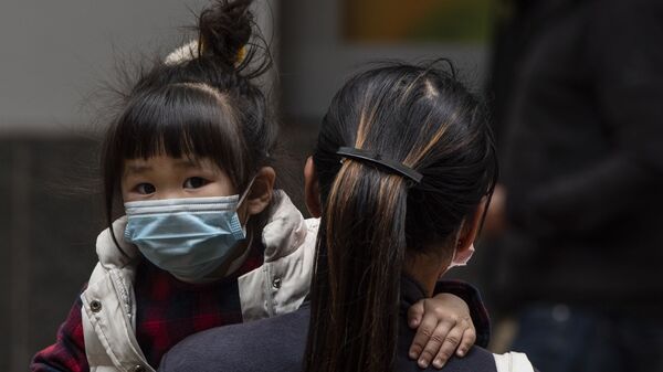 Девочка в защитной маске на руках у матери на одной из улиц в Гонконге. - Sputnik Армения