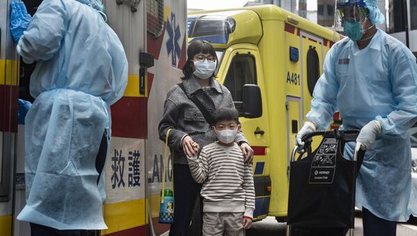 Женщина с ребенок в защитных масках рядом с автомобилем скорой помощи на одной из улиц в Гонконге. - Sputnik Армения