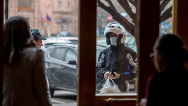 Доставщик еды в каске, маске и перчатках - кадр дня (19 марта 2020). Еревaн - Sputnik Армения