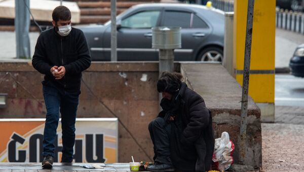 Молодой человек в защитной маске проходит мимо бездомной женщины - Sputnik Արմենիա