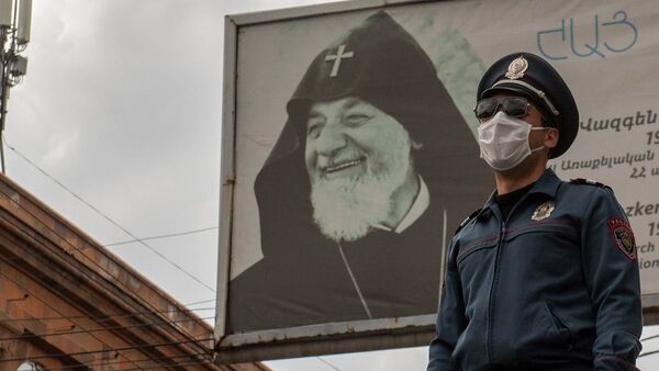 Полицейский в защитной маске на фоне баннера во время чрезвычайной ситуации (25 марта 2020). Ереван - Sputnik Արմենիա