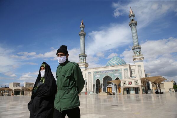 Пожилая пара в защитных масках рядом с мечетью Фатимы Масуме в городе Кум (24 марта 2020). Иран - Sputnik Армения