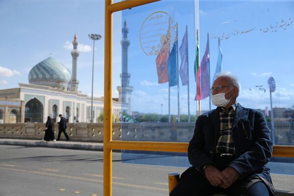 Мужчина в защитной маске на автобусной остановке в городе Кум (24 марта 2020). Иран - Sputnik Армения