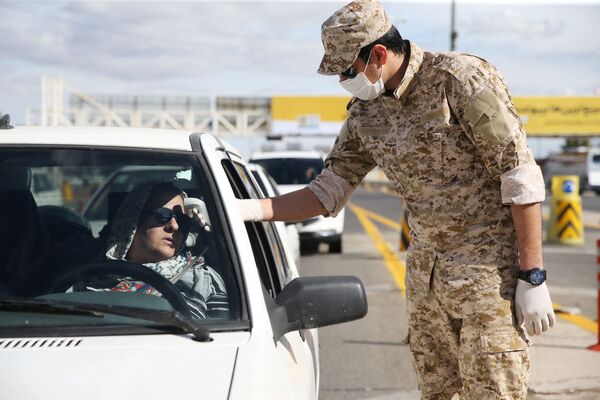 Военнослужащий Корпуса Стражей Исламской революции (КСИР) измеряет температуру водителя на въезде в город Кум (24 марта 2020). Иран - Sputnik Армения