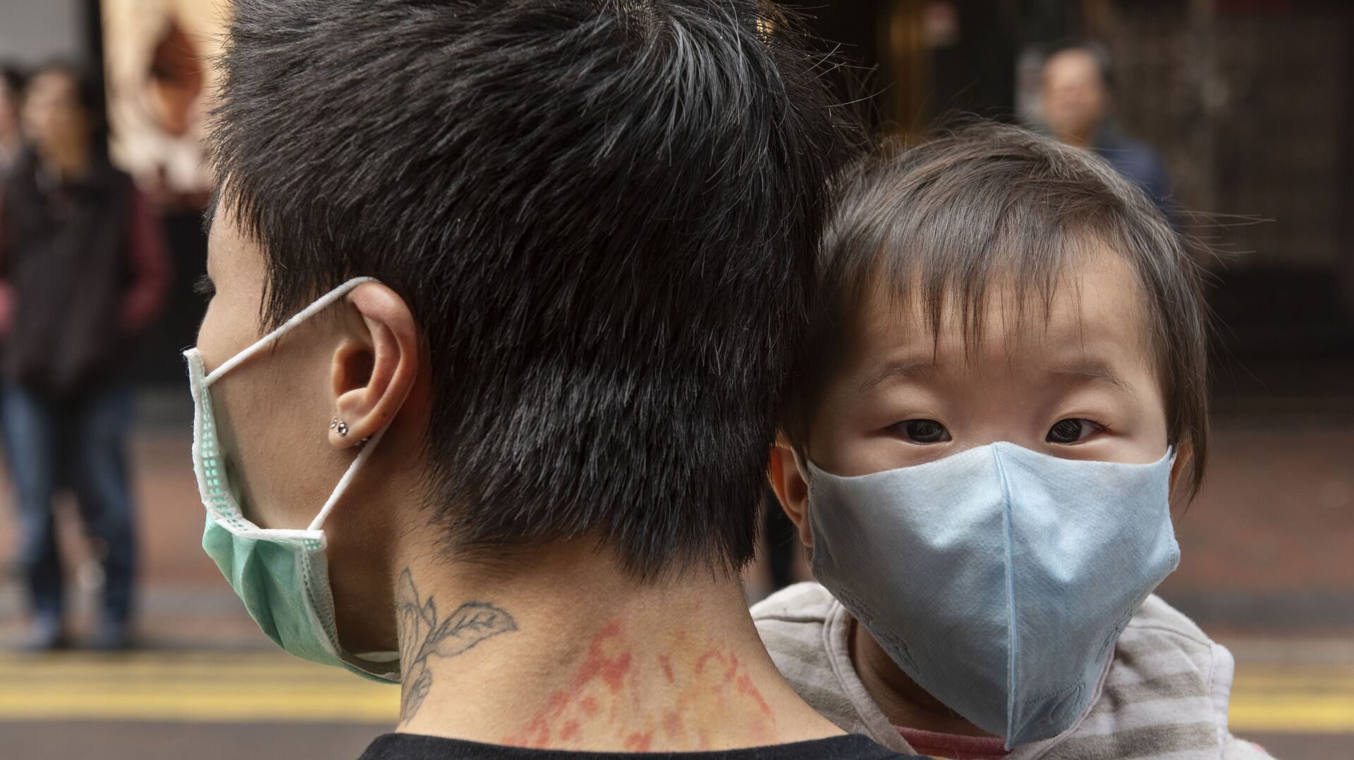 Ребенок в защитной маске на руках отца на одной из улиц в Гонконге - Sputnik Армения, 1920, 12.06.2022