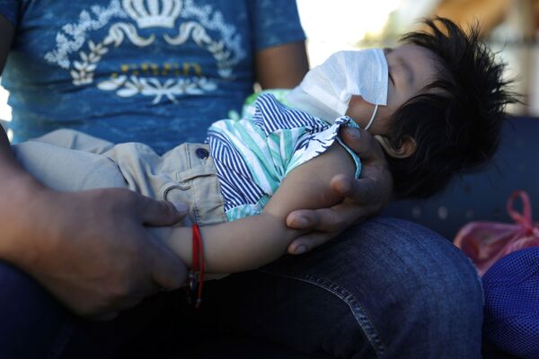 Мужчина со спящим ребенком в медицинской маске на руках в Сантьяго, Чили - Sputnik Армения