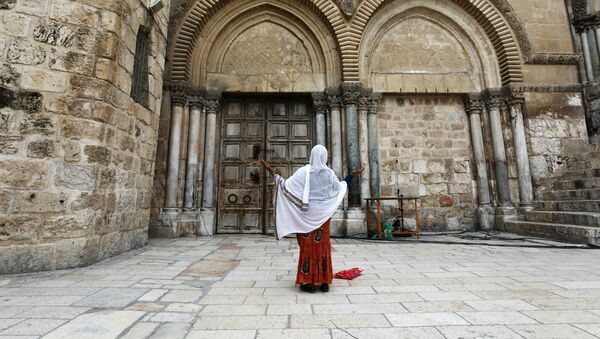 Женщина молится рядом с закрытыми дверями Храма Гроба Господня во время празднования Страстной пятницы на фоне вспышки коронавируса (17 апреля 2020). Иерусалим - Sputnik Армения