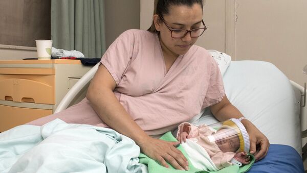 Женщина с новорожденным ребенком в защитной маске в отделении неонатологии мексиканской больницы в Сан-Хосе, Коста-Рика - Sputnik Армения