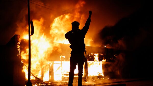 Протестующий у горящего здания во время демонстрации в связи со смертью Джорджа Флойда, убитого полицейским (29 мая 2020). Миннеаполис - Sputnik Армения