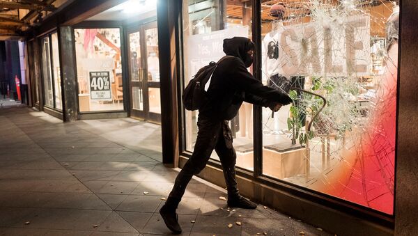 Протестующий разбивает витрину одного из предприятий во время демонстрации в связи со смертью Джорджа Флойда, убитого полицейским в Миннеаполисе (29 мая 2020). Лос-Анджелес - Sputnik Армения