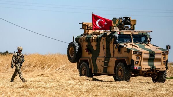 Американский солдат идет рядом с турецкой военной машиной во время совместного патрулирования с Турцией в сирийской деревне Аль-Хашиша на окраине города Таль-Абьяд вдоль границы с Турцией (8 сентября 2019). Сирия - Sputnik Армения