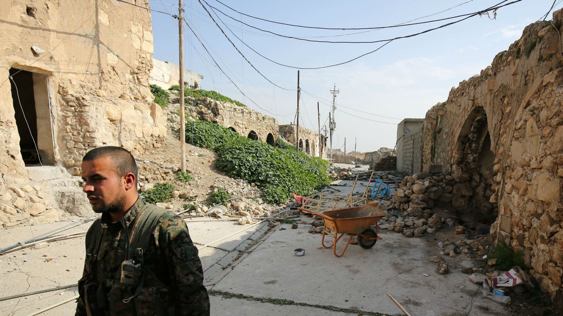Боец езидов из базирующихся в Сирии Народных подразделений защиты, более известных как YPG, идет по разрушенным улицам Синджара (29 января 2015). Ирак - Sputnik Армения, 1920, 01.02.2023