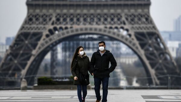 Пара в защитных масках гуляет возле Эйфелевой башни (18 марта 2020). Париж - Sputnik Армения