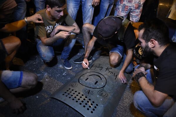 Демонстранты рисуют смайлики на вырванном у полицейского щите - Sputnik Армения