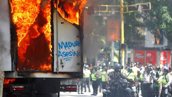 Сотрудники сил безопасности собираются рядом с правительственным грузовиком, который был подожжен во время митинга против правительства президента Венесуэлы Николаса Мадуро в Каракасе, Венесуэла - Sputnik Армения