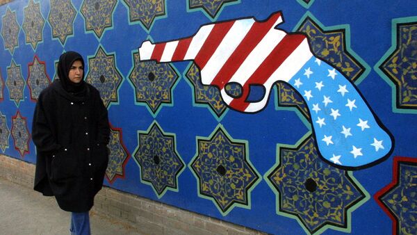 Женщина проходит мимо бывшего здания посольства США в Иране, на стене которого нарисован револьвер цветами американского флага - Sputnik Армения